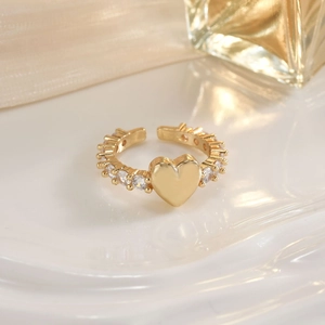 Macro shot of gold heart ring with pavé cubic zirconia accents on a silk background