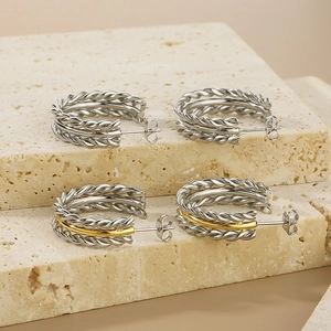 Detailed view of twisted C-shaped earrings in silver and gold-tone polished metal