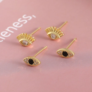 18k gold plated evil eye stud earrings set with crystal inlay on a pink background