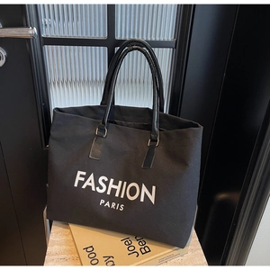 Detail einer großen schwarzen Canvas-Tragetasche mit Fashion Paris Aufdruck auf Kochbuch
