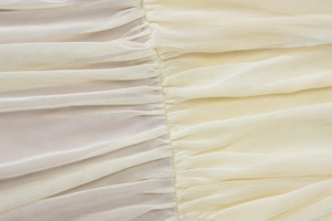 Close-up of the delicate beige mesh fabric detailing with fine pleats and high-quality stitching