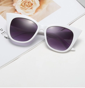 Detail of trendy white cat-eye sunglasses featuring purple gradient lenses on a magazine