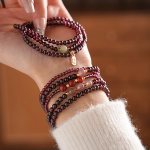 Detail of garnet beaded bracelet with a lucky gold charm on a knitted sleeve
