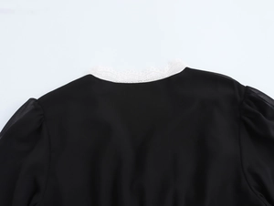 Close-up of black chiffon dress featuring white lace collar and puff sleeve details