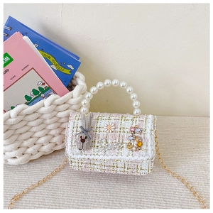 Close-up of pink tweed girl's bag with pearl handle, bow bunny, and gold chain strap