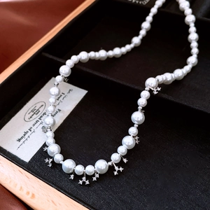 Detail of pearl necklace with zircon flower charms in a black velvet jewelry box