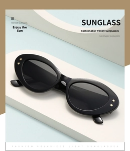 Detailed macro view of black oval sunglasses featuring gold star metal accents on the frame