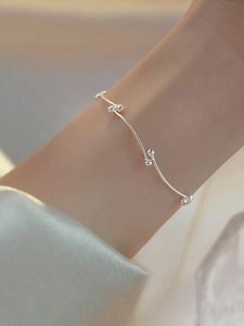 Minimalist silver bead knot bracelet shown on a wrist with delicate metallic details