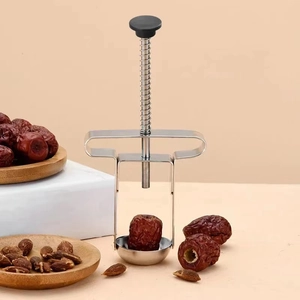 Macro shot of stainless steel cherry pitter tool removing pits from fresh red dates