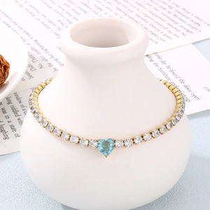 Detail of a heart-shaped blue gemstone necklace on a ceramic vase with a vintage book