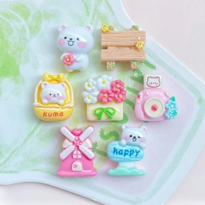 Macro detail of assorted mini resin cartoon charms including bears and flowers on a white plate