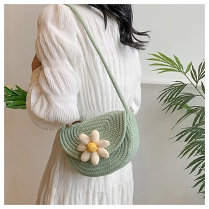 Side view of a light green woven saddle bag with a daisy flower on white dress