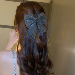 Elegant large black rhinestone bow hair clip styled on wavy brown hair from a back view