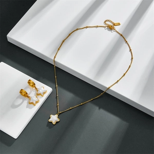Detailed view of gold star pendants with white pearlescent inlay on white geometric props