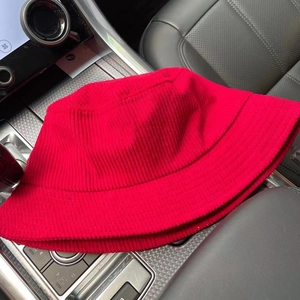 Classic red corduroy bucket hat with adjustable strap on a car dashboard stylishly displayed