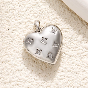 Macro shot of silver heart pendant with diamonds on a textured beige surface