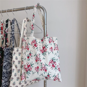 Detail of floral cotton tote bags with vintage tulip prints hanging on a rack