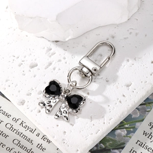 Detail of silver keychain with black crystal bow pendant on minimalist stone