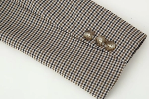 Macro detail of houndstooth wool fabric blazer cuff with three dark resin buttons