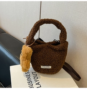 Close-up of deep brown teddy faux fur bucket bag with cute bear pendant detail