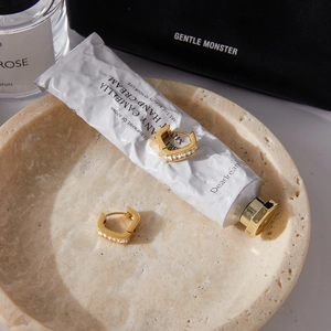 Gros plan de boucles d'oreilles en U dorées avec zircons sur un support en pierre