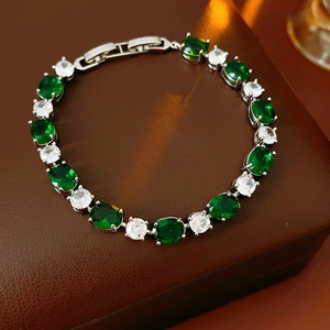 Bracelet argenté avec pierres émeraude et zircons clairs sur une boîte de luxe brune