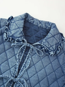 Detail of ruffled collar and lace-up closure on quilted washed denim cotton jacket