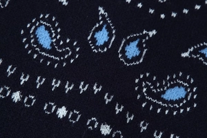 Macro view of blue knit cardigan with detailed paisley patterns and geometric stitching