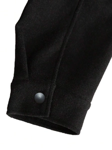 Close-up of black wool jacket cuff with matte button and detailed stitching texture