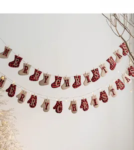 Détail de guirlande de Noël en feutre avec chaussettes et moufles à carreaux sur mur blanc