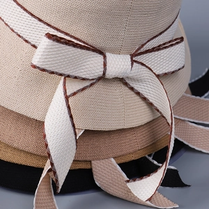 Detailed macro view of woven sun hats showing texture and chic beige ribbon with grid pattern