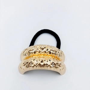 Detailed close-up of golden alloy hair ring with molten texture and black elastic band