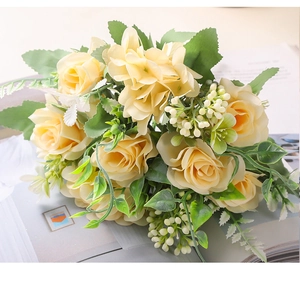 Vista detallada de un ramo de rosas amarillas artificiales con hojas y pequeñas flores
