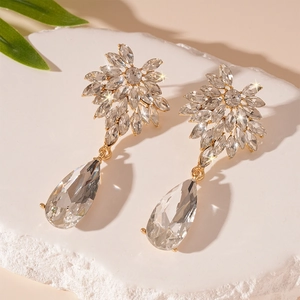 Close-up of sparkling flower-shaped stud and large teardrop crystal earring on stone