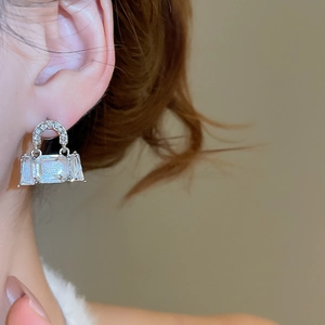 Close-up of sparkling square crystal earrings worn by a model in soft daylight