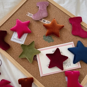 Macro shot of colorful velvet Christmas star and sock ornaments on a wooden board