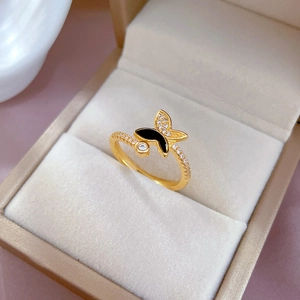 Adjustable gold butterfly ring with black enamel and micro-pave crystals on beige velvet