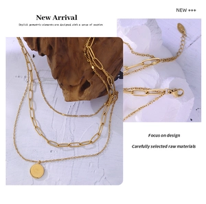 Macro detail of layered gold stainless steel necklace with Carpe Diem coin pendant