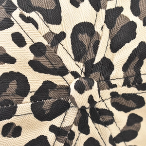 Macro detail of leopard print baseball cap crown showing twill fabric texture and top button