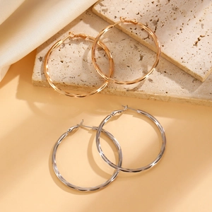 Detail of gold and silver large hoop earrings with diamond-cut texture on stone and silk