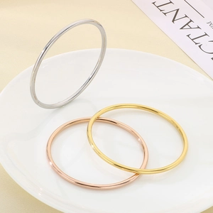 Polished 3mm stainless steel bangles in silver, gold, and rose gold in a ceramic dish
