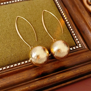 Gros plan de boucles d'oreilles boules dorées à texture brossée sur velours vert
