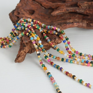 Handmade colorful tourmaline beaded necklace with gold spacers on natural wood stand