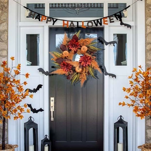 Détail d'une couronne d'Halloween avec citrouilles et baies sur une porte d'entrée noire