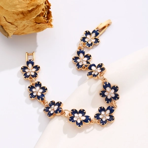Detailed close-up of blue and white enamel flower bracelet with crystals and gold finish