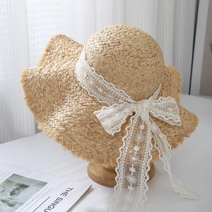 Cappello di paglia con fiocco in pizzo bianco e bordi sfilacciati per la protezione solare