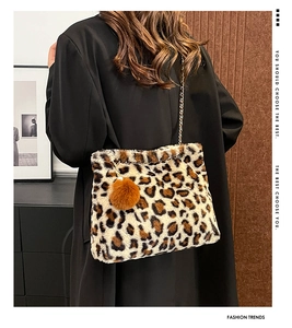 Close-up of leopard print plush bag with gold chain strap and fluffy pompom accessory