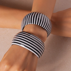 Dettaglio del set di bracciali larghi in acrilico con motivi a strisce bianche e nere