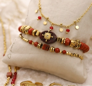 Détail de bracelets perlés faits main et colliers dorés sur coussin de bijoux beige