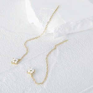 Detail of gold floral tassel earrings with four-leaf clover zircon pendant and chain
